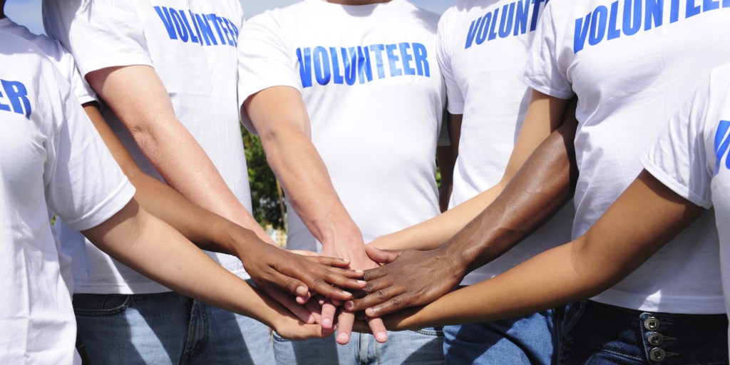 multi ethnic volunteer group hands together